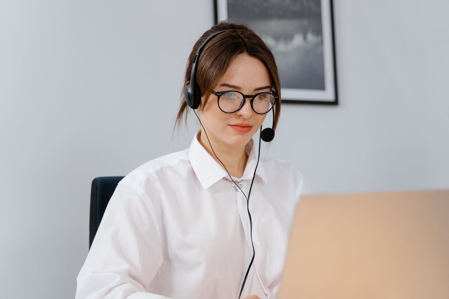 A woman wearing a headset while working at a laptop