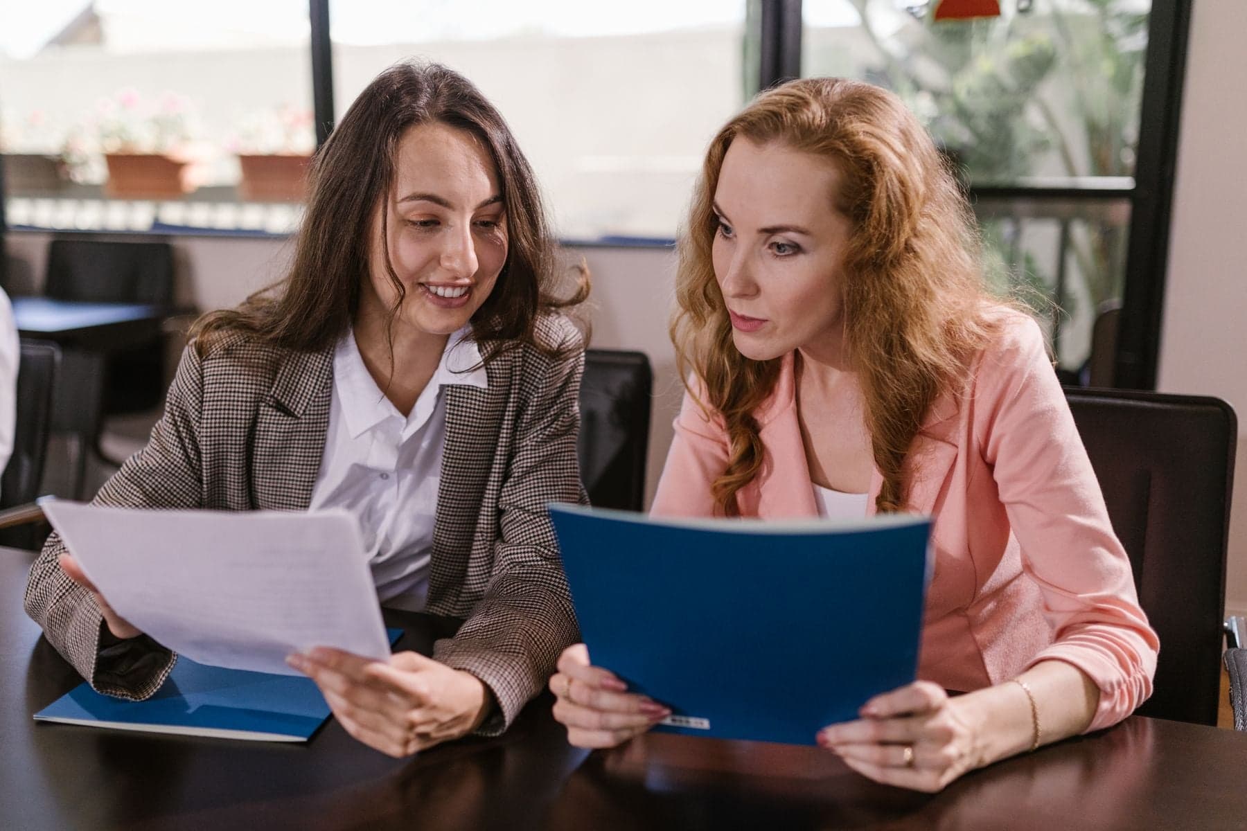 Two women reviewing documents and folders together at a desk